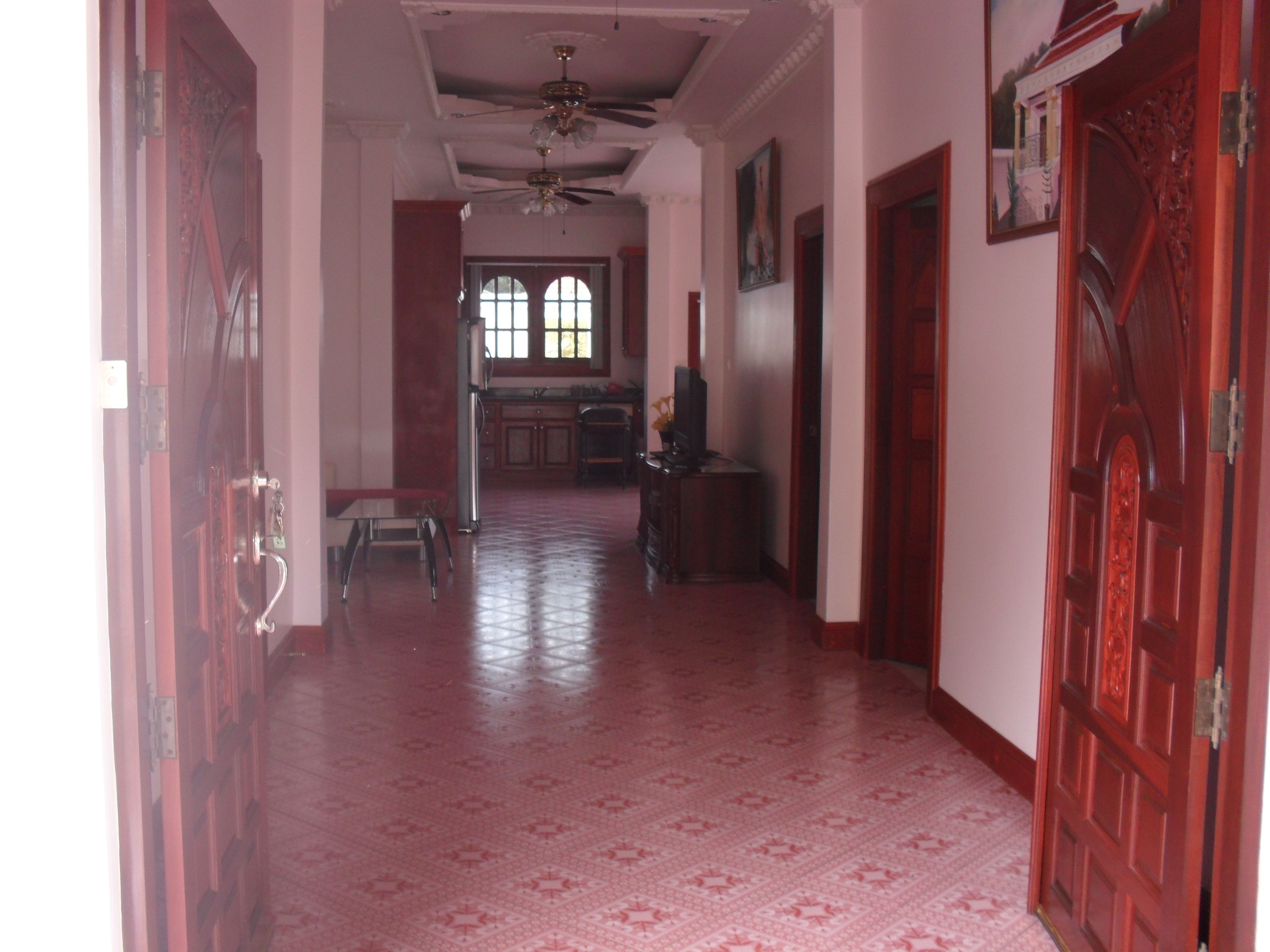 A hallway with patterned flooring, a ceiling fan, and a door with intricate design.