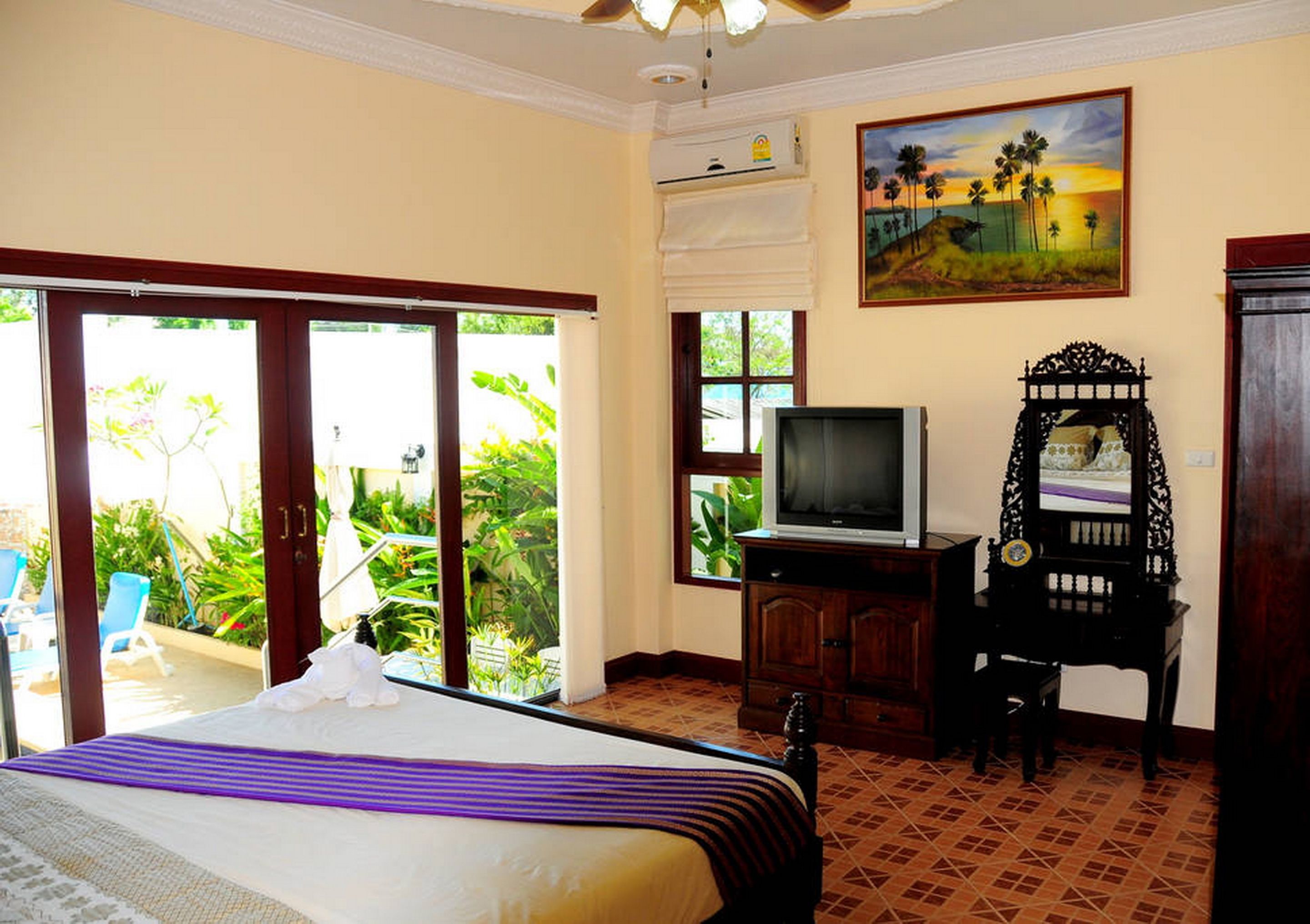 A hotel room with a bed, a television, a desk, and a painting on the wall.