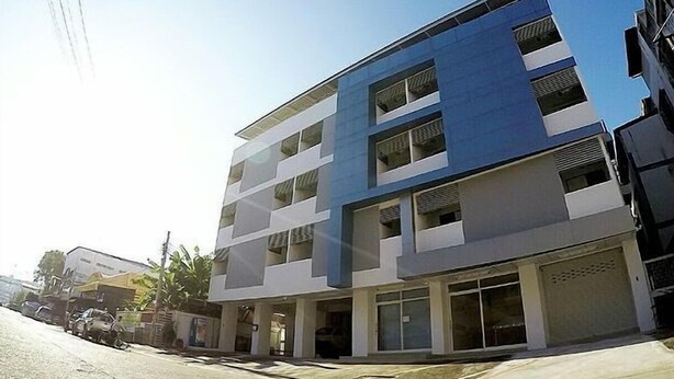 A multi-story building with a blue and white facade, large windows, and a flat roof.