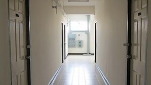 A hallway with white tiled floors and doors on both sides.
