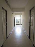 Un pasillo con pisos de baldosas blancas y puertas a ambos lados.