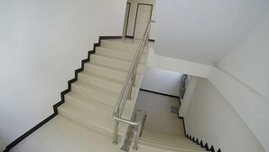 A staircase with a handrail, white walls, and a door at the top.