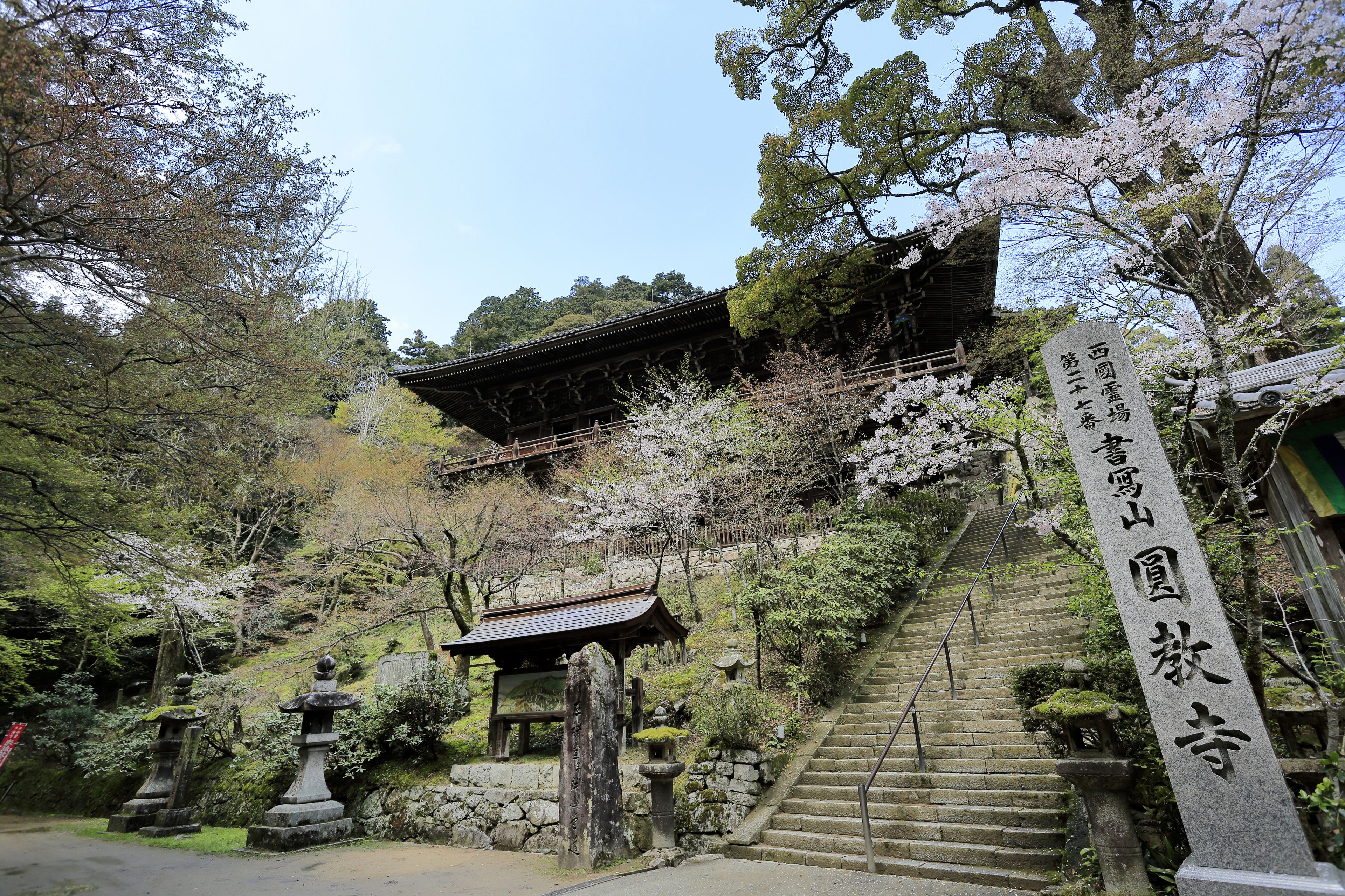 A traditional Japanese temple with a stone staircase leading up to a wooden gate.