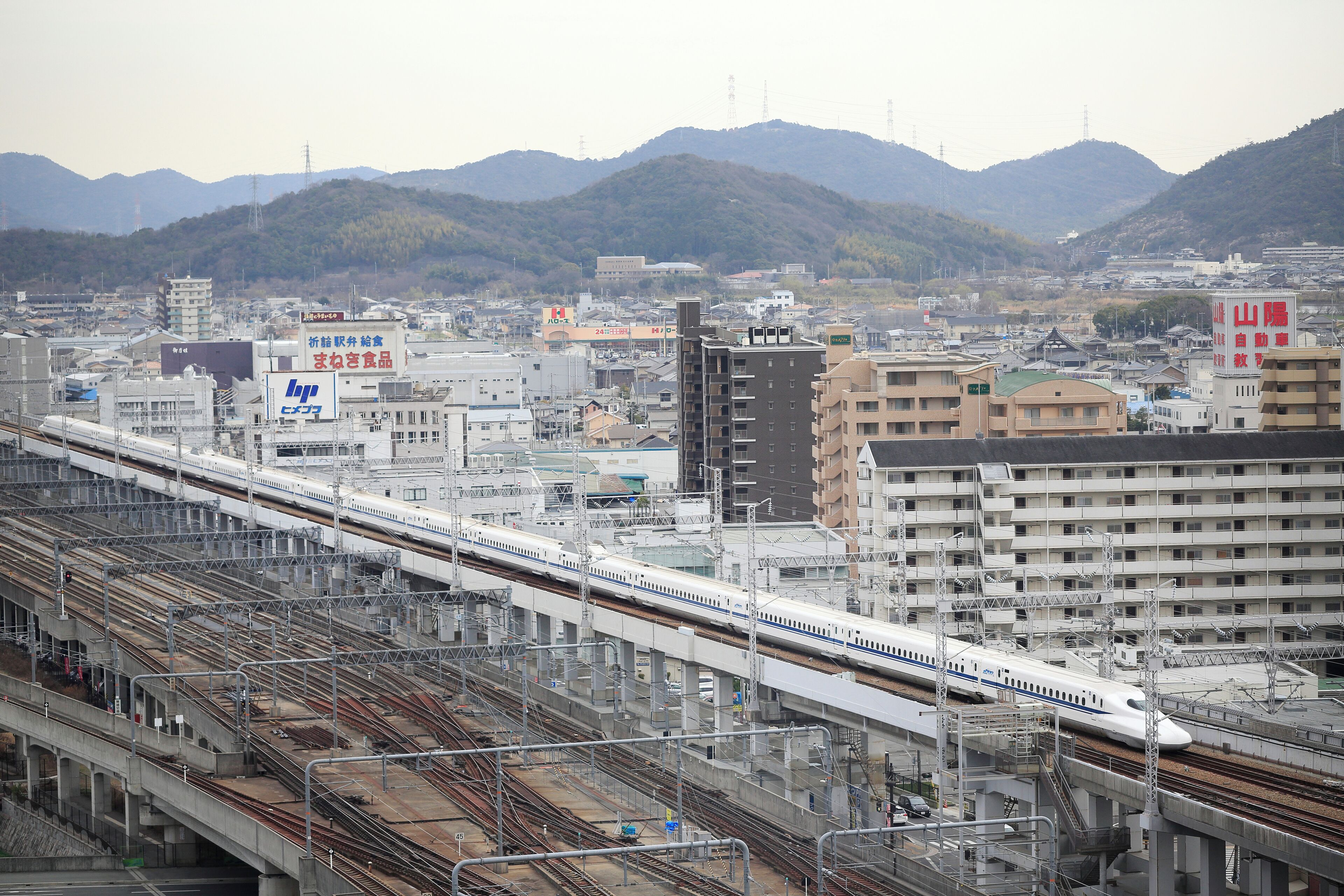 A train station with multiple tracks and a train in motion.