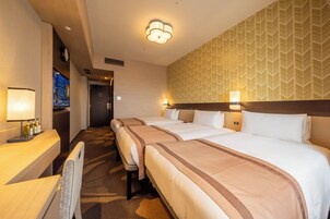 Habitación de hotel con dos camas, un escritorio con lámpara, televisor y pared con diseño.