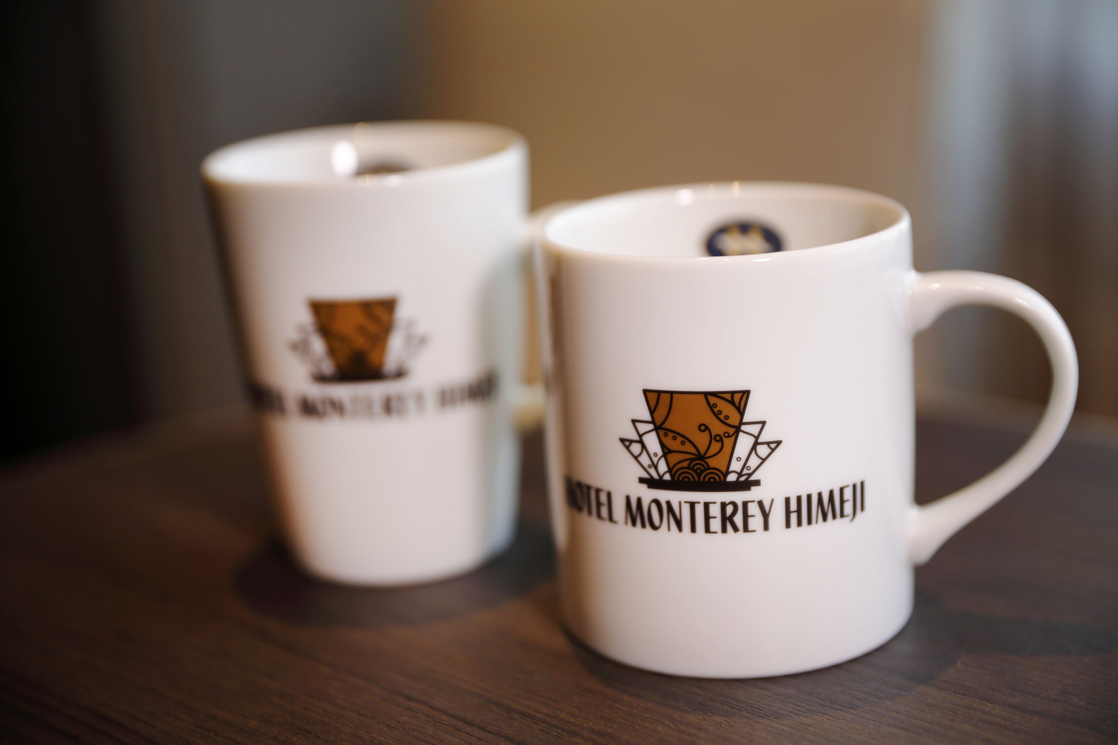 Dos tazas blancas con logotipos y texto.