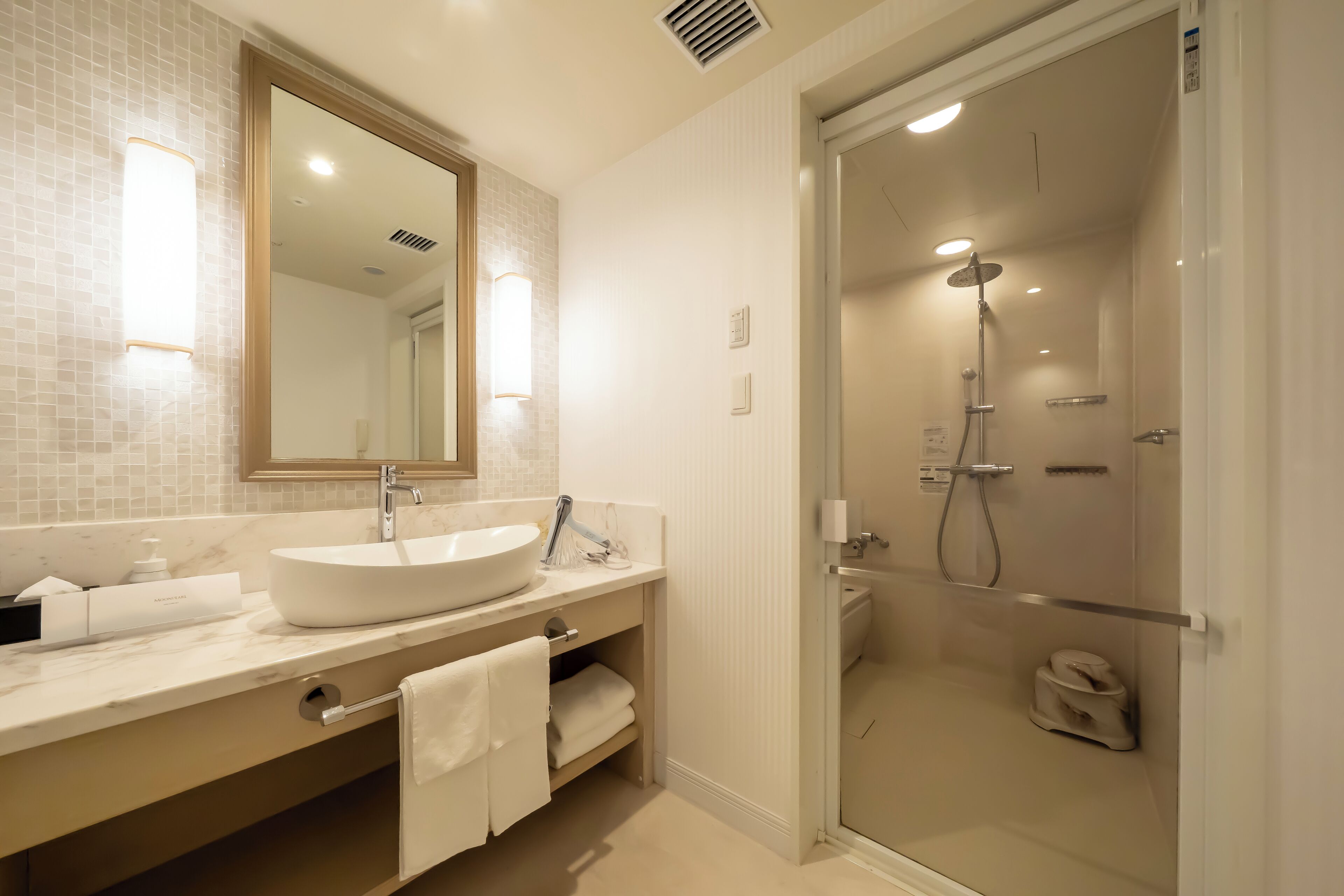 A modern bathroom with a large sink, mirror, and walk-in shower.
