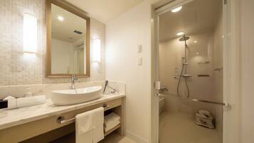 A modern bathroom with a large sink, mirror, and walk-in shower.