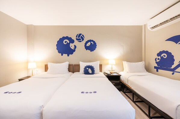 Habitación de hotel con tres camas, cada una con ropa de cama blanca y un diseño de almohada único. Hay dos mesitas de noche con lámparas, y un equipo de aire acondicionado instalado en la pared.