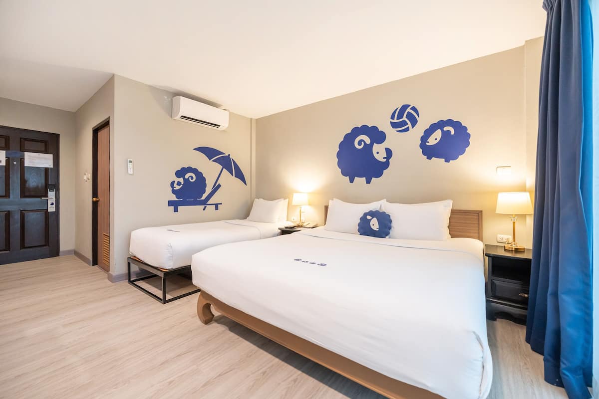 Habitación de hotel con dos camas, aire acondicionado empotrado y adhesivos decorativos de ovejas y paraguas.