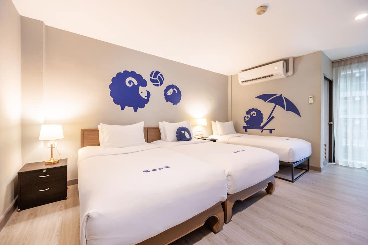 Una habitación de hotel con dos camas, una mesita de noche y un mural en la pared.