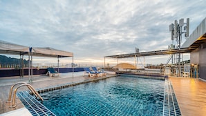 Un espace piscine avec une eau d’un bleu limpide, des chaises longues et un coin salon abrité.