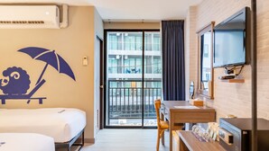 Une chambre d’hôtel équipée d’un lit, d’un bureau, d’une chaise, d’une télévision et d’un balcon offrant une vue sur la ville.