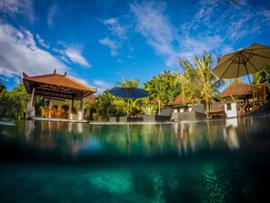 A pool area with lounge chairs, umbrellas, and a gazebo. - Bingin Garden (Pecatu)