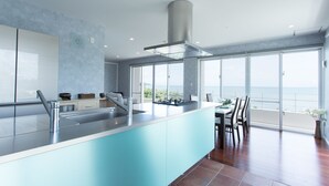 A modern kitchen with a large island, stainless steel appliances, and a view of the sea through large windows. - Suite villa Yagaji (Nago)