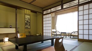 Una habitación japonesa tradicional con suelo de tatami, una mesa baja y puertas correderas.