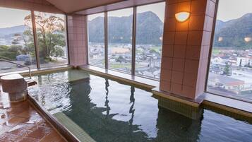 Piscina interior com vista para uma cidade e montanhas através de grandes janelas.