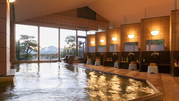 Un área de spa con una amplia piscina interior, zonas de estar y vistas a árboles y montañas a través de grandes ventanales.