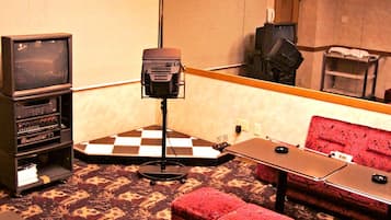 Une pièce avec un sol à carreaux, un canapé rouge, une petite table, un téléviseur et un système audio.