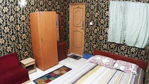 Een slaapkamer met een bed, een kledingkast, een rode bank en een vloerkleed met dessin.