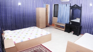 Een slaapkamer met een bed, een kledingkast, een dressoir, een spiegel en een raam met gordijnen.