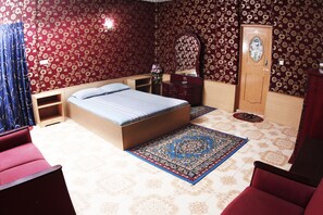 Une chambre à coucher avec un lit, une commode, un miroir, une porte et une chaise rouge.