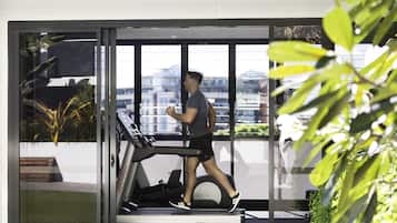 A person using a treadmill in a modern indoor space with large windows and indoor plants.