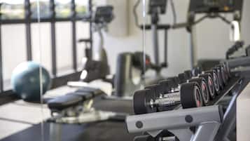Una palestra con attrezzature per esercizi, tra cui manubri e un tapis roulant.