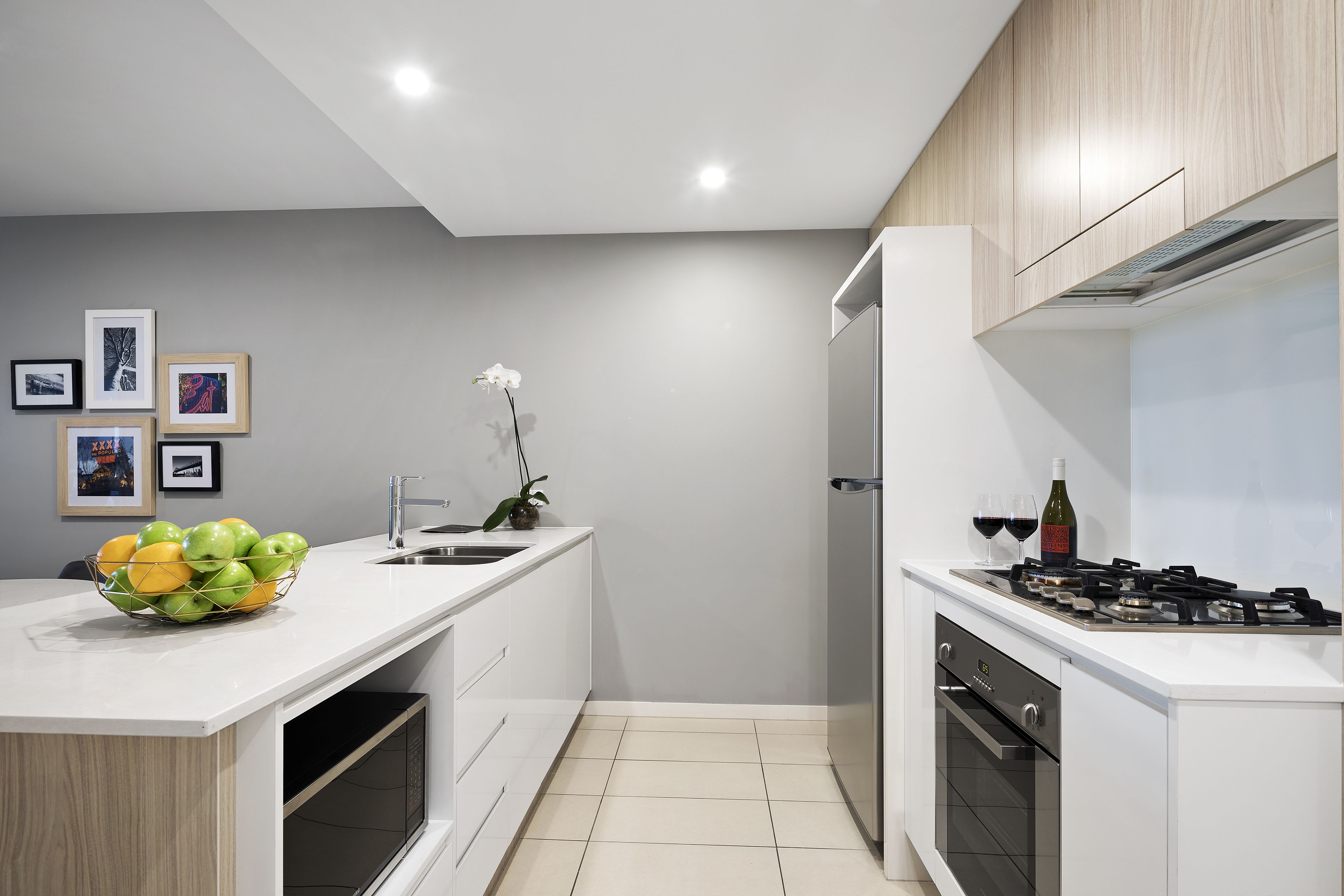 A modern kitchen with white cabinetry, a built-in oven, and a gas stove.
