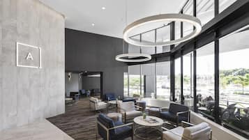 A modern lounge area with seating, a coffee table, and a large window offering a view of the city.