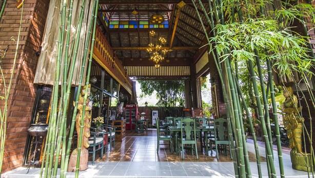 An indoor dining area with bamboo decor, brick walls, and a tiled floor. - Irawadee Resort (Mae Sot)