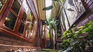 A narrow stone pathway flanked by large windows and lush greenery, leading to a door. - Irawadee Resort (Mae Sot)