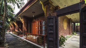 A traditional wooden building with a large open doorway, a brick pathway, and a small porch area. - Irawadee Resort (Mae Sot)