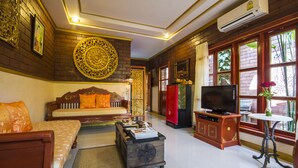 A traditional room with a sofa, a television, and a small table with a vase. - Irawadee Resort (Mae Sot)