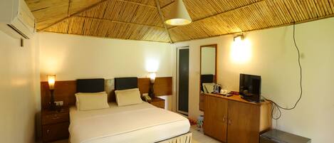 A hotel room with a bed, bedside tables, a wardrobe, a television, and a small refrigerator.