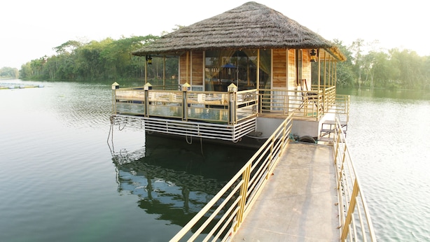 A wooden structure with a thatched roof on a dock extending into calm water, surrounded by greenery. - Rangauti Resort (Moulvibazar Sadar)