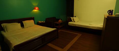 A bedroom with a bed, a desk, a chair, and a small table.