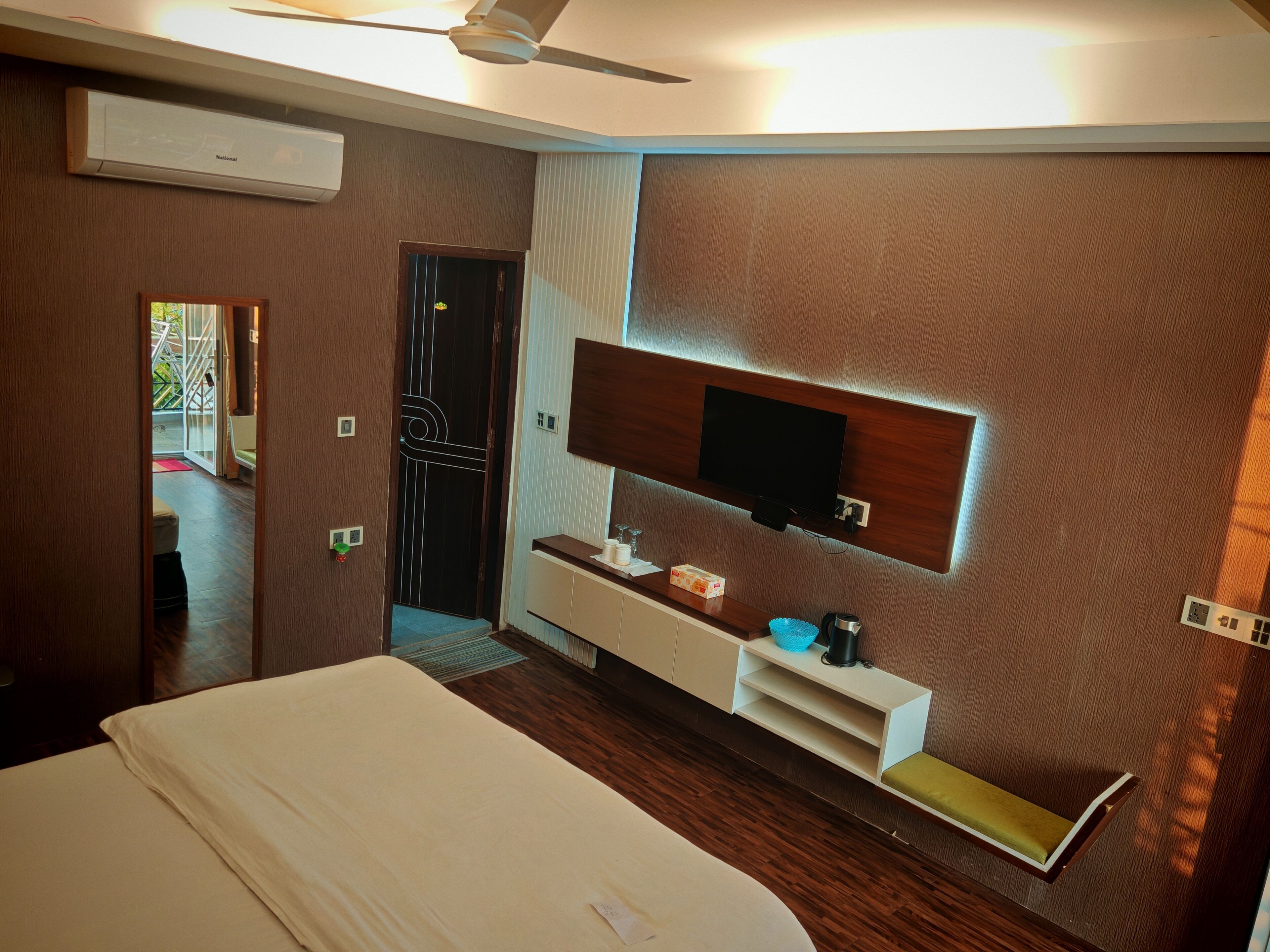 Une chambre d’hôtel moderne dotée d’un grand lit, d’un téléviseur intégré, d’une coiffeuse avec miroir et d’un petit coin salon.