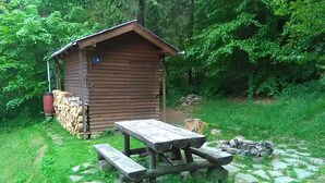 A wooden cabin with a picnic table and benches, surrounded by a stone pathway and lush greenery. - Chata Pohoda Slovenský Raj (Spišské Tomášovce)