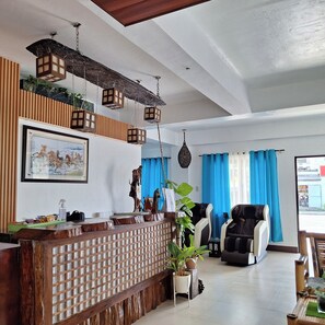 A reception area with a wooden counter, a framed painting, and hanging lanterns. - Mayon Lodging House (Daraga)