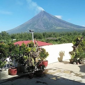 A volcano with a red-roofed building in the foreground. - Mayon Lodging House (Daraga)