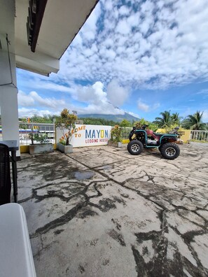 A sign for 'Come to Mayon Lodging House' with a view of a mountain and a parked quad bike. - Mayon Lodging House (Daraga)
