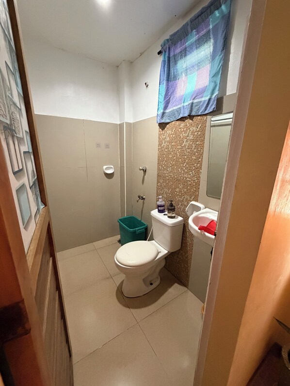 Un baño pequeño con inodoro, lavabo y un bote de basura verde.