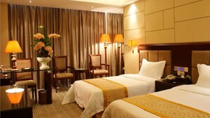 A hotel room with two beds, a desk, chairs, a lamp, and a vase of flowers. - Vienna Hotel Xi'an Railway Station (Xi'an)