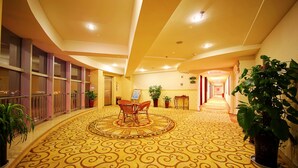 A hotel lobby with a patterned carpet, a reception desk, and potted plants. - Vienna Hotel Xi'an Railway Station (Xi'an)