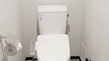 A small, white, modern bathroom with a toilet, a toilet paper holder, and a radiator.
