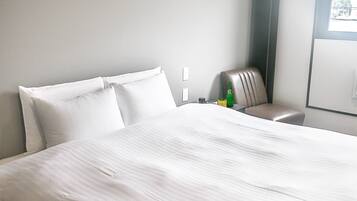 Une chambre d’hôtel avec un grand lit, une chaise, une bouteille et un verre sur la table de chevet.