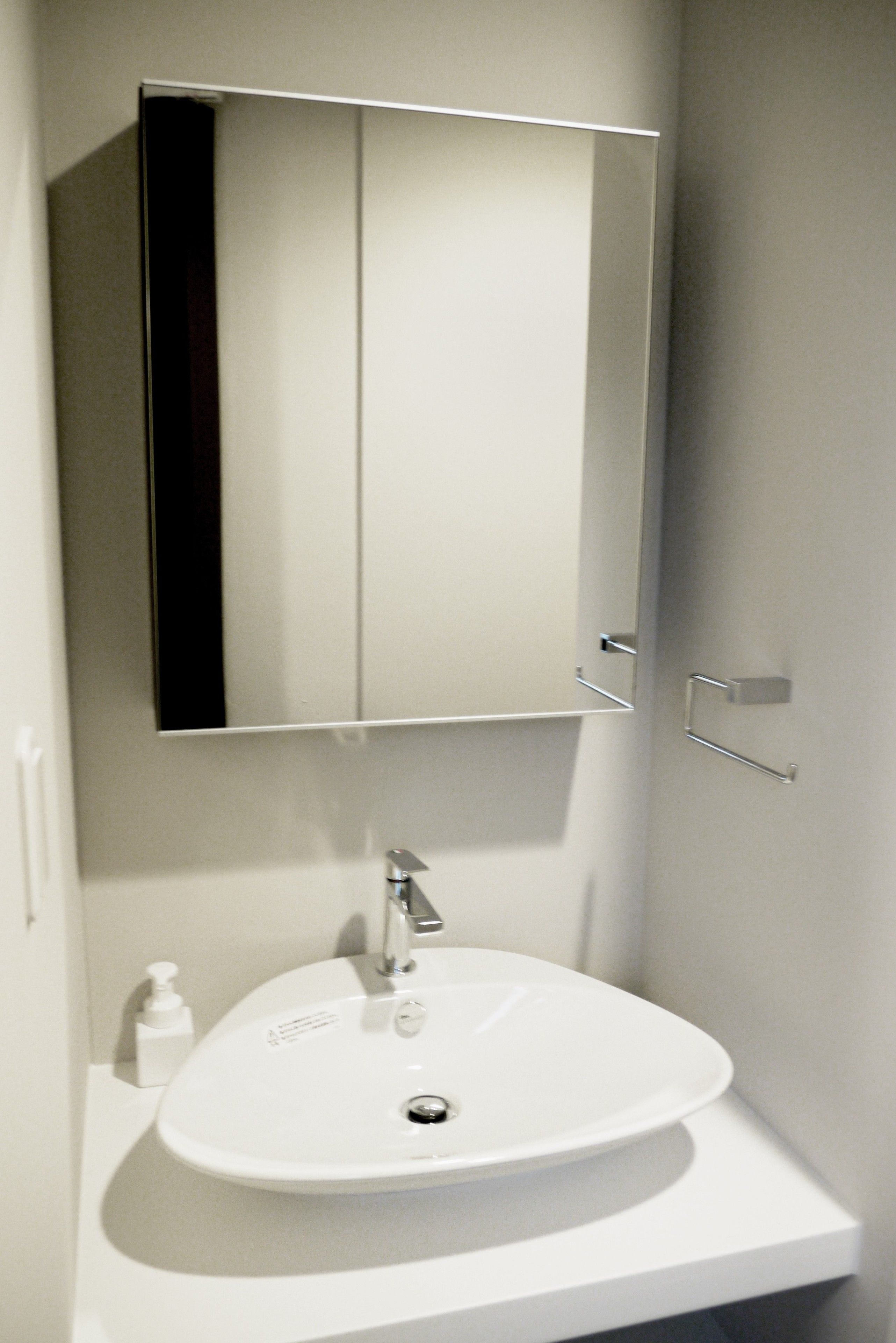 A bathroom with a white sink, a mirror, and a door.