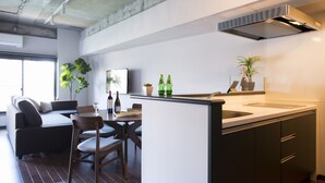 A modern kitchen with a central island, a dining area with a sofa and chairs, and a large window providing natural light. - A Good Day Fukuoka Riverside (Fukuoka)