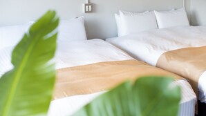A hotel room with two beds, white bedding, and a large green plant in the foreground. - A Good Day Fukuoka Riverside (Fukuoka)